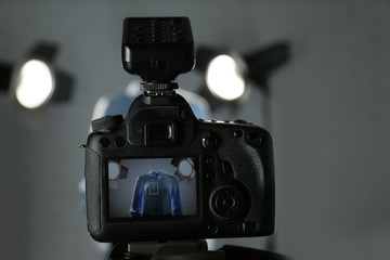 Ghost mannequin with stylish clothes and professional lighting equipment in modern studio, focus on camera. Fashion photography