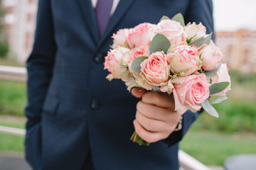 wedding bouquet of roses in the hands of the groom
