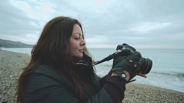 woman with a camera in her hands against the backdrop of the seascape