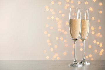 Glasses of champagne on grey table against blurred lights. Space for text