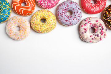 Delicious glazed donuts on white background, flat lay. Space for text