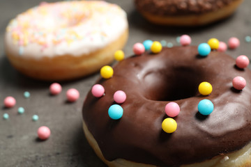 Yummy donut with colorful sprinkles on dark table, closeup