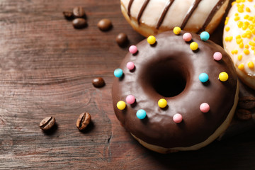 Yummy donuts with colorful sprinkles on wooden table, closeup. Space for text