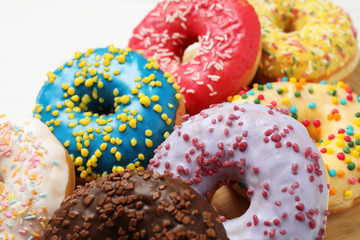 Yummy donuts with sprinkles on white table, closeup