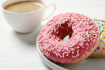 Yummy donuts with sprinkles on white wooden table, closeup