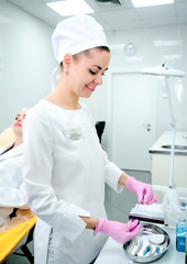Cosmetologist doctor standing near patient and holding botox syringe wearing gloves before operation, injections under skin. Beautician preparing for lips augmentation. Beauty aesthetic treatment.