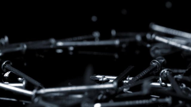 Steel nails falling over black background. Slow motion.