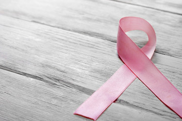 Pink breast cancer awareness ribbon on a wooden table. Concept of medicine, health care. Space for...