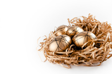 Easter golden decorated eggs in nest on white background . Minimal easter concept copy space for text. Top horizontal view, flatlay.