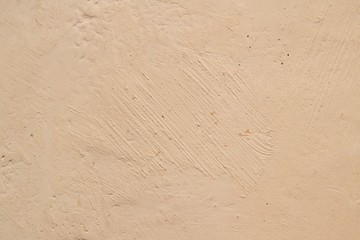 The plaster is beige, slightly pinkish in color, the surface is not uniform old, antique retro design with uneven stripes, casually smeared. Background.