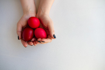In the hands of a person are Easter eggs in red shades on a white background