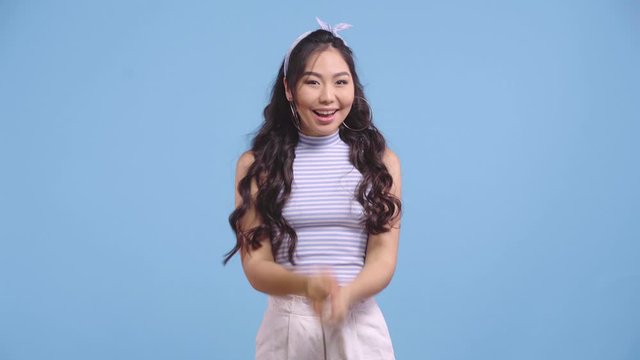 excited asian girl gesturing and celebrating isolated on blue