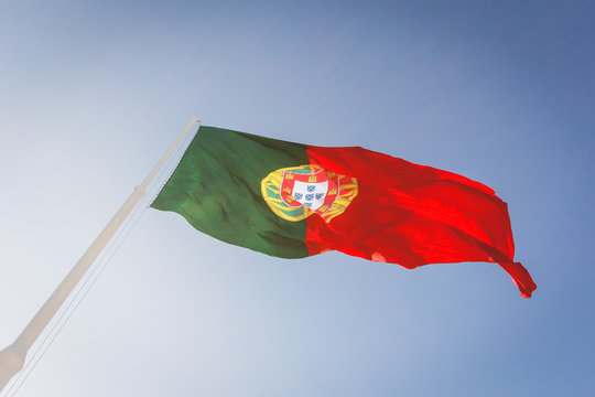 Grande bandeira de Portugal hasteada sob o céu azul da cidade de Lisboa