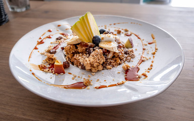 Granola with yogurt, fruit and nuts on a white dish