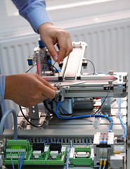 Closeup of male technician repairing automation system's electronic card by allen key. 