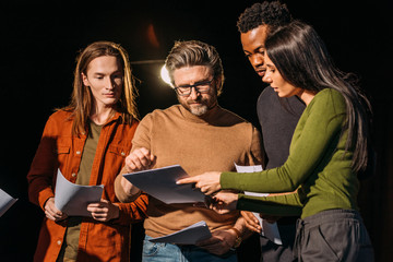 theater director, multicultural actors and actress rehearsing with scripts on stage