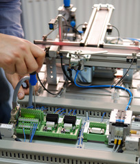 Closeup of male technician repairing automation system's electronic card by screwdriver. 