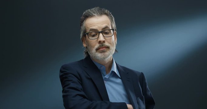 Portrait of rich handsome businessman of middle-age in glasses and suit taking out money from pocket and proposing. Financial successful man in business style giving dollars to camera like offering.