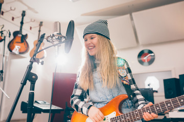 Fototapeta na wymiar teenage girl singing and playing guitar at the music studio. recording song .