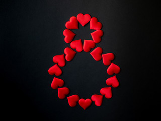 Digital symbol 8, laid out with red silk hearts on a black background. March 8. International Women's Day