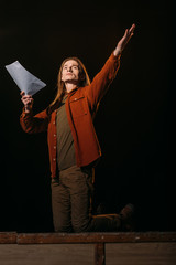 handsome actor with screenplay playing on stage during rehearse