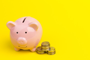Piggy bank with coin pile on yellow background, space for text. Finance, saving money
