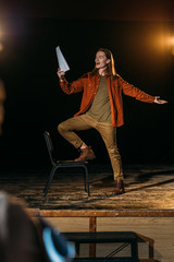 handsome actor with screenplay playing on stage during rehearse in theatre