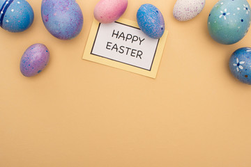 Top view of card with happy easter lettering and Easter eggs on beige background