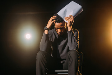 stressed african american actor holding scenario on stage during rehearse