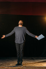 emotional african american actor holding scenario on stage during rehearse