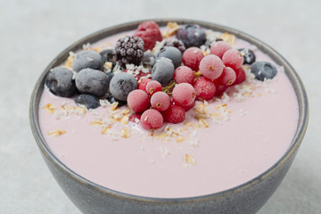Healthy breakfast berry smoothie bowl topped with frozen blueberries, currants red, blackberries, raspberries, Chia seeds and granola. 