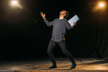 african american actor holding scenario and standing on stage during rehearse in theatre - obrazy, fototapety, plakaty