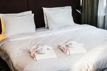 large bed with pillows in the hotel and bathrobes with Slippers for guests