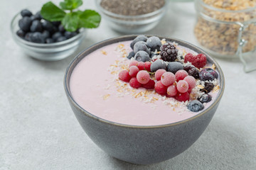 Healthy breakfast berry smoothie bowl topped with frozen blueberries, currants red, blackberries, raspberries, Chia seeds and granola. 