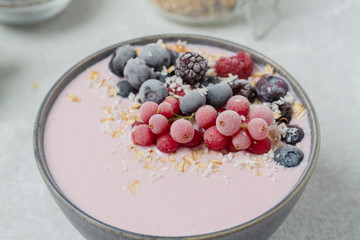 Healthy breakfast berry smoothie bowl topped with frozen blueberries, currants red, blackberries, raspberries, Chia seeds and granola. 