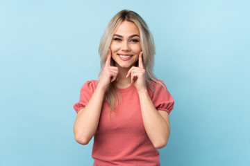 Teenager girl over isolated blue background smiling with a happy and pleasant expression