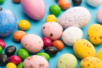 Fototapeta na wymiar Selective focus of bright colorful sweets and easter eggs on blue background
