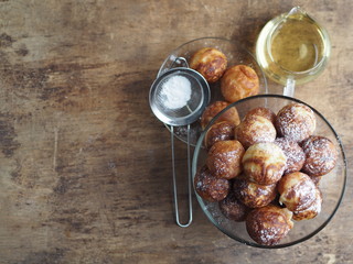 Homemade baking donuts. Deep-fried, in vegetable oil in a frying pan. Holiday and everyday food. Place for text. Brown wooden background.