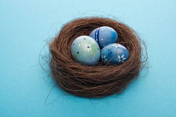 Fototapeta premium Close up view of Easter eggs in nest on blue