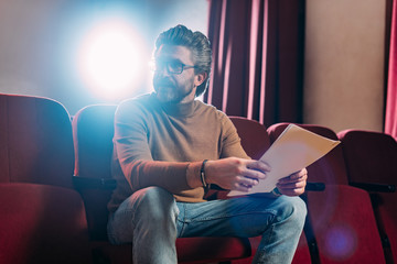 mature stage director with scenario in theater with backlight