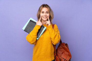 Teenager Russian student girl isolated on purple background smiling with a happy and pleasant expression