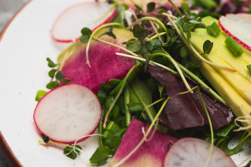 close up view of fresh radish salad with greens and avocado
