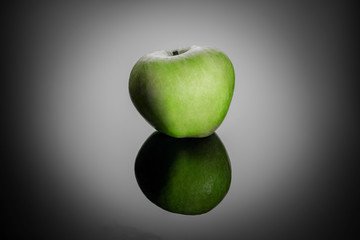 Green apple with reflection, on a black background, shallow depth of field. Concept, healthy food, lifestyle.