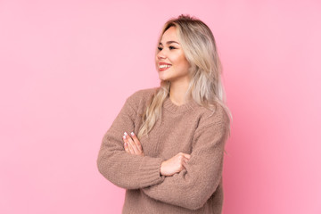 Teenager blonde girl wearing a sweater over isolated pink background happy and smiling
