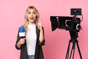 Reporter woman holding a microphone and reporting news over isolated pink background intending to realizes the solution while lifting a finger up