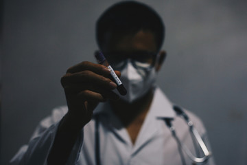 Doctor in personal protective suit holding COVID19 blood sample tube on white background