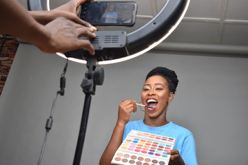 beautiful young black woman filming a makeup tutorial to post online
