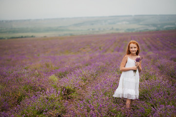 Cute red-haired girl in lavender field in rainy day