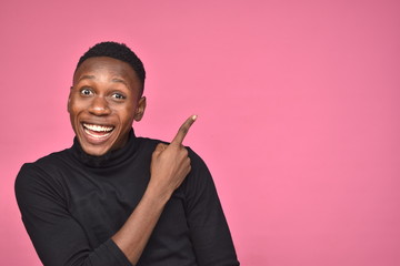 handsome young black man looking excited and pointing to space on his side
