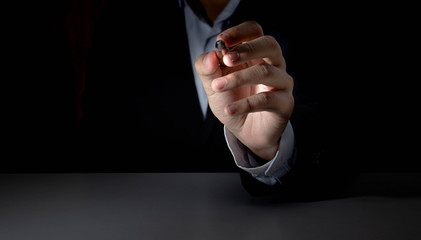 A businessman with a pen to identify things with a black background